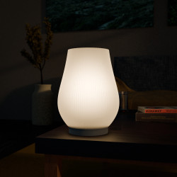 Weiße RGB-Dekolampe in tropfenförmigem Design auf einem Tisch